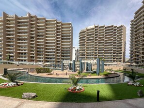 A high-rise residential building with multiple balconies, a central swimming pool, and surrounding greenery. - Brand New 6 Bedroom Penthouse (Puerto Peñasco)