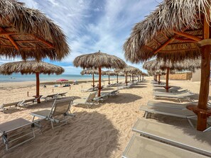 A beach with thatched umbrellas and sun loungers. - Brand New 6 Bedroom Penthouse (Puerto Peñasco)