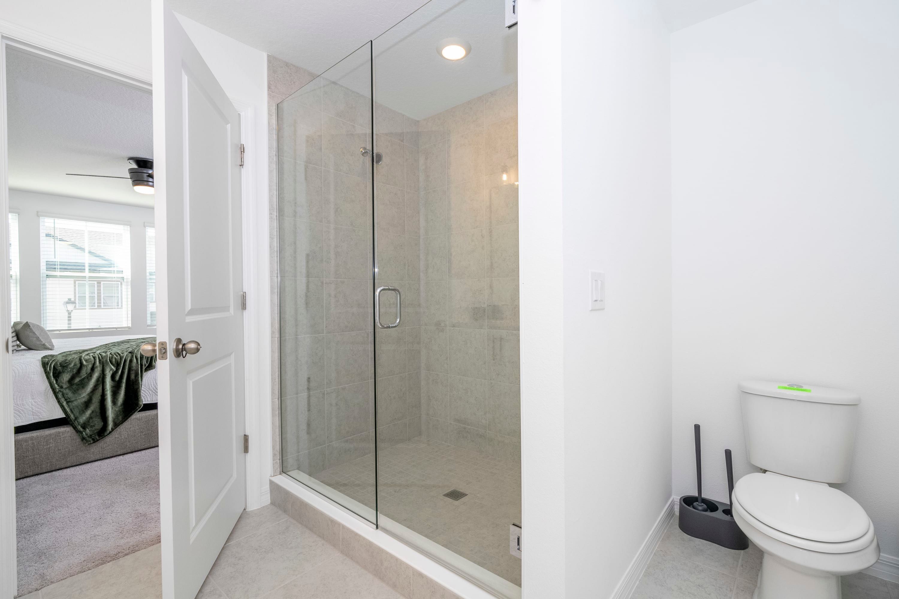 A modern bathroom with a glass-enclosed shower, a toilet, and a visible bathtub.