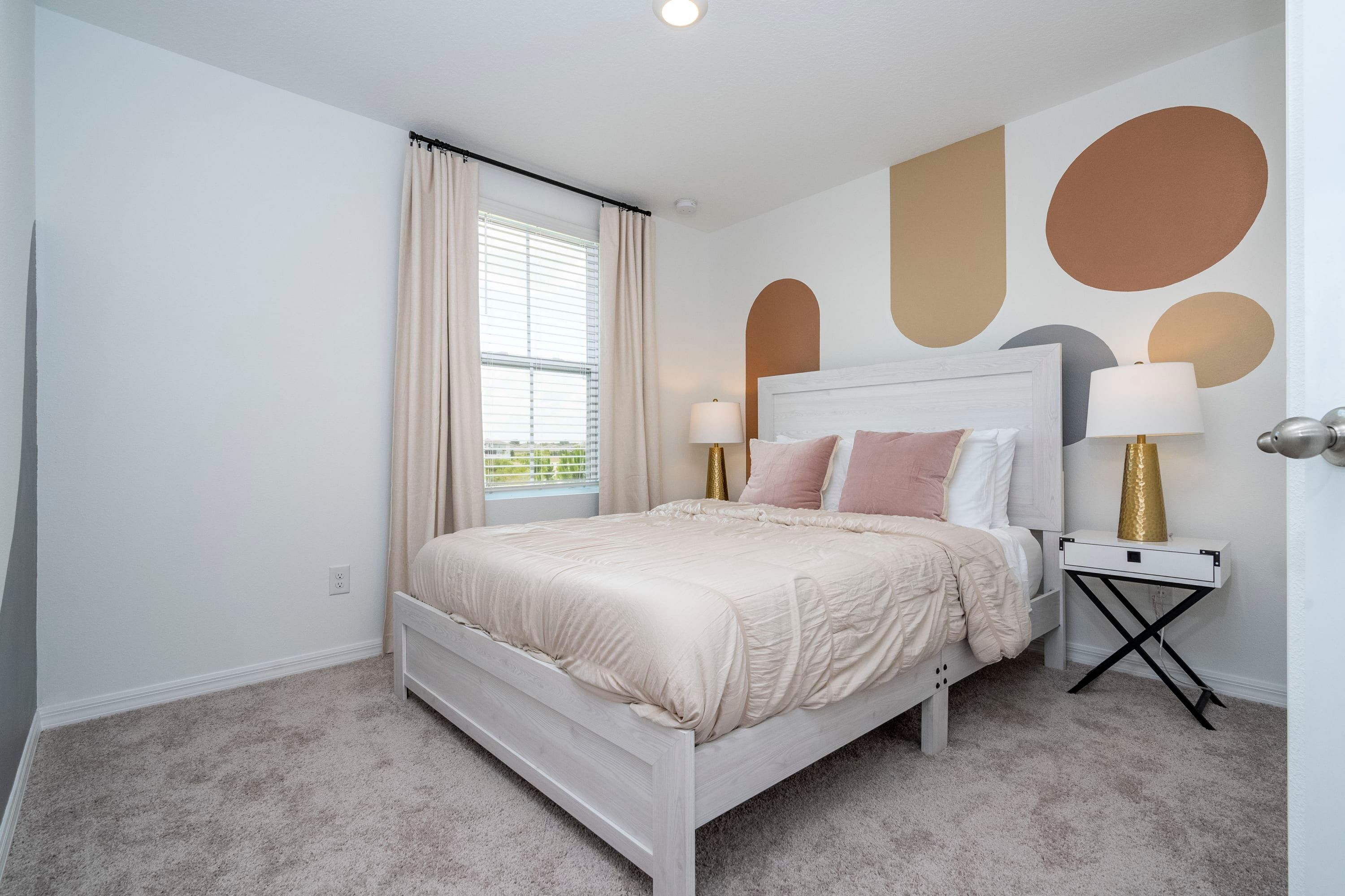 A bedroom with a bed, bedside tables, and a window with curtains.