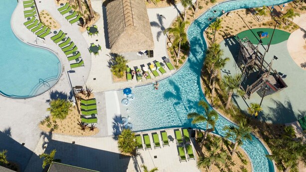 Eine Vogelperspektive eines Resorts mit mehreren Schwimmbecken, Liegebereichen und Palmen.