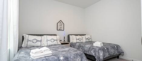 A bedroom with two beds, each with a galaxy-themed bedspread, white pillows, and a bedside table with a lamp.