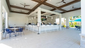 An outdoor patio area with ceiling fans, white chairs, and tables. - Stunning 5Bd Close to Disney at Storey Lake 3199 (Kissimmee)