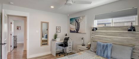 Un dormitorio con cama, escritorio, silla y ventilador de techo.