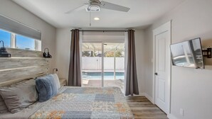 A bedroom with a bed, a ceiling fan, a window, and a view of a pool. - Family Retreat By Old Town w Pool (Phoenix)