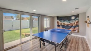 A ping pong table in a room with large sliding glass doors leading to a backyard. - Family Retreat By Old Town w Pool (Phoenix)