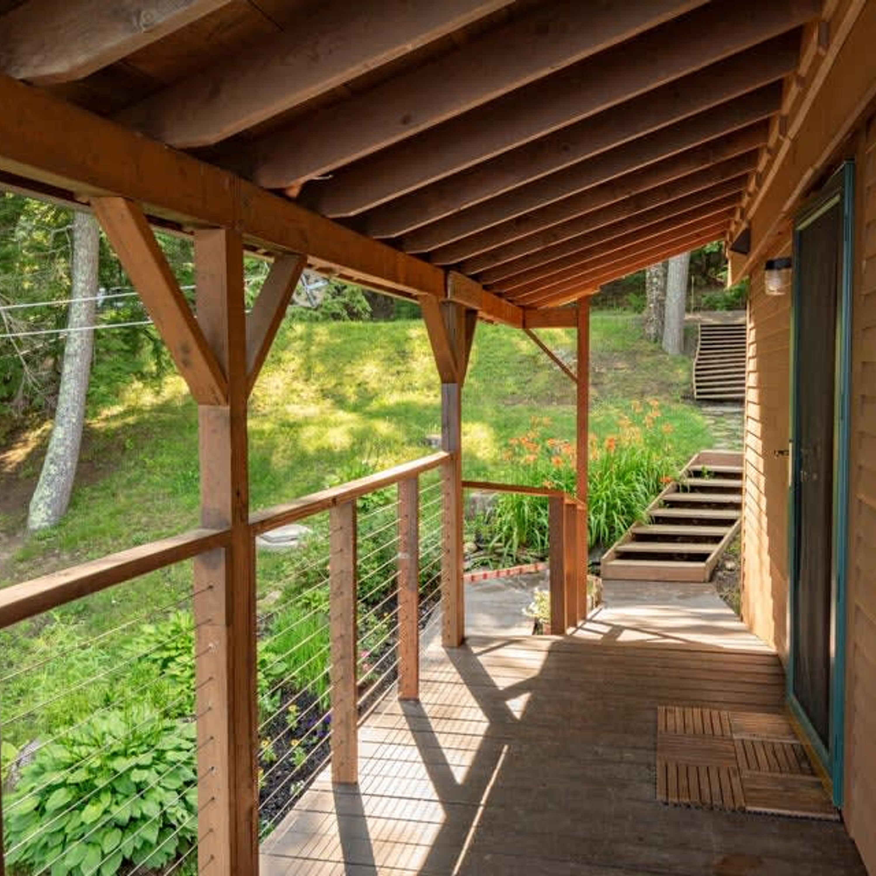 A wooden deck with a metal railing, leading to a door.