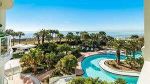 Un resort con piscina curva, palmeras y vista al océano.