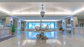 Un amplio vestíbulo con una fuente decorativa central, techos altos e iluminación moderna.