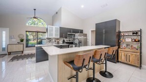 A modern kitchen with a central island, bar stools, and built-in appliances. - Swiss 49 - Lake Denise (Clermont)