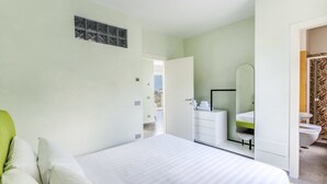 A bedroom with a bed, a dresser, a mirror, and a bathroom with a toilet and sink.