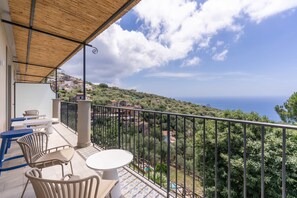 A balcony with outdoor furniture, a view of a coastal town, and a clear sky. - Le Arcate Sea La Vie (Massa Lubrense)