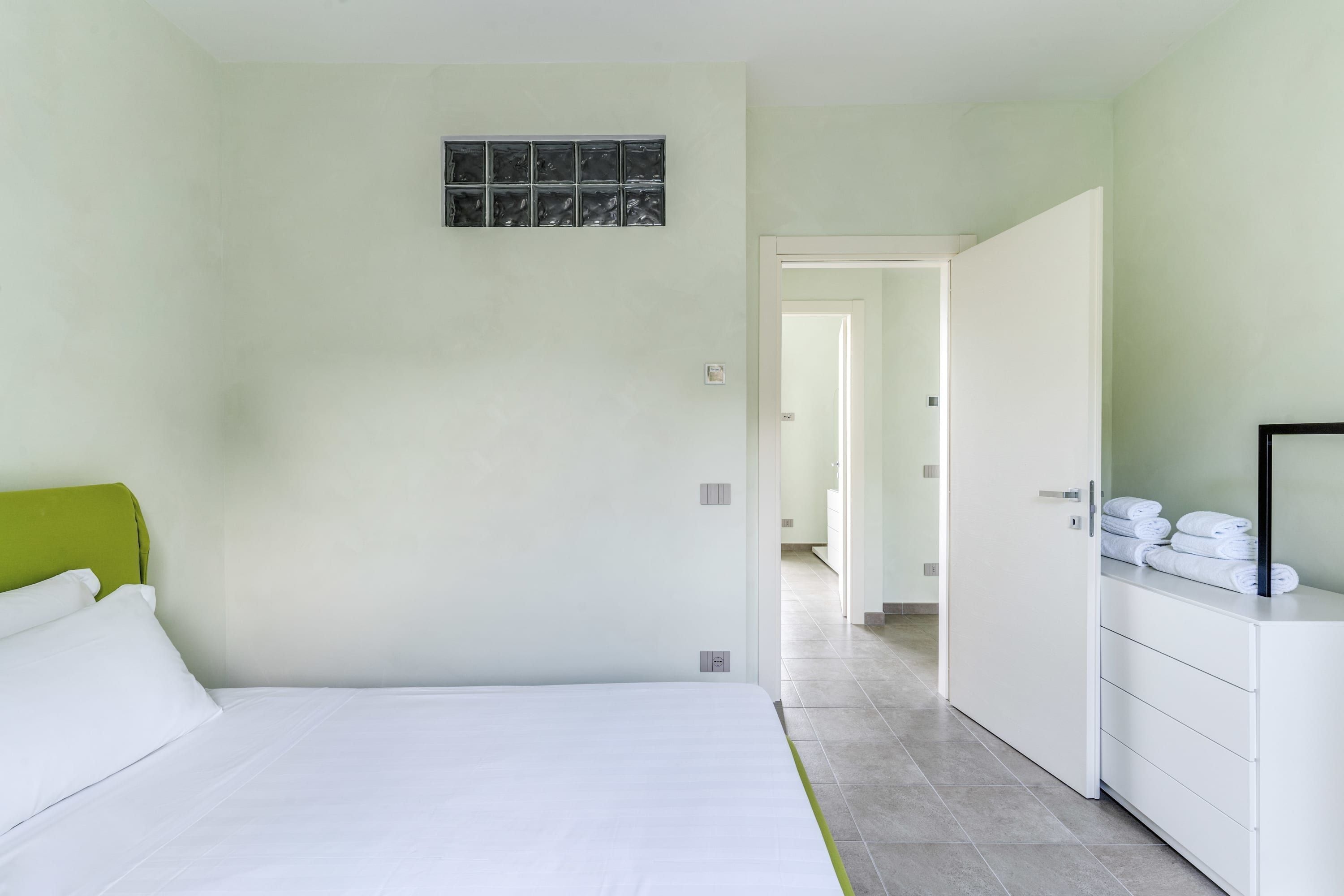 Une chambre d’hôtel avec un lit, une commode et une salle de bain, visibles à travers une porte ouverte.