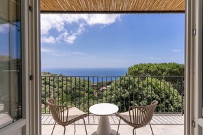 A balcony with a table and two chairs, overlooking a scenic view of the sea and greenery. - Le Arcate Sea La Vie (Massa Lubrense)