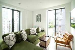 Un salon moderne avec un canapé vert, une table basse en bois et un fauteuil en cuir.