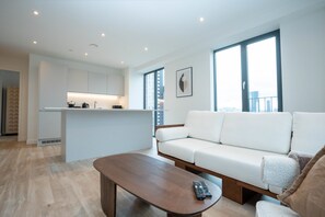 Una sala de estar moderna con un sofá, una mesa de centro y una zona de cocina con encimera y armarios.
