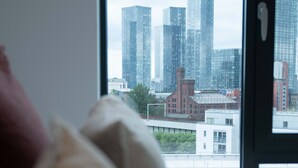 Un lit donnant sur une vue de la ville à travers une fenêtre.