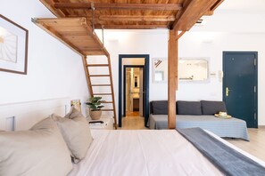 A bedroom with a bed, a sofa, a ladder, a potted plant, and a door. - Unik Vacation Oli in Tarragona (Tarragona)