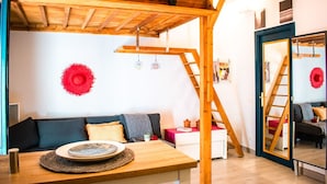 A cozy room with a wooden ceiling, a sofa, a table with a plate, and a ladder. - Unik Vacation Oli in Tarragona (Tarragona)