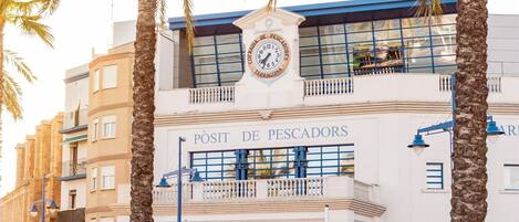 A building with a sign reading "POSIT DE PESCADORES" and palm trees in the foreground.