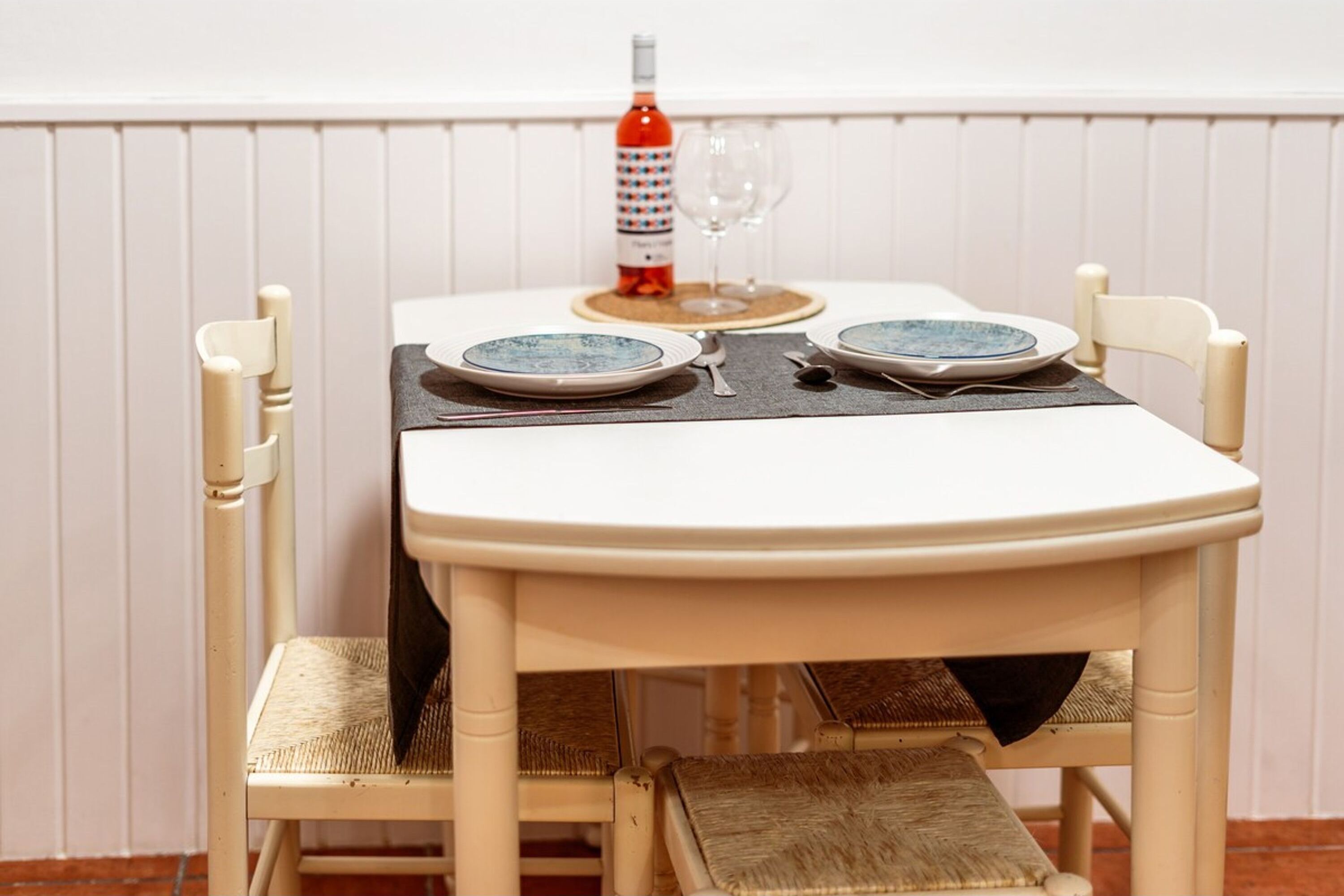 A dining table set with plates, a wine glass, and a bottle of wine.