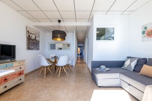 A modern living space with a dining area, a sofa, and a television. - Unik Vacation Rovellat (Tarragona)