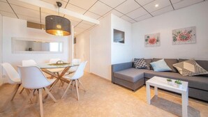 A modern living room with a grey sofa, white chairs, a glass dining table, and a small white coffee table. - Unik Vacation Rovellat (Tarragona)