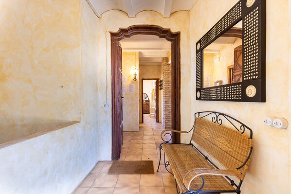 A hallway with a bench, a welcome mat, and a mirror on the wall.