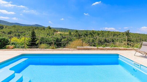 Ein Schwimmbecken mit freiem Blick auf eine gebirgige Landschaft im Hintergrund.