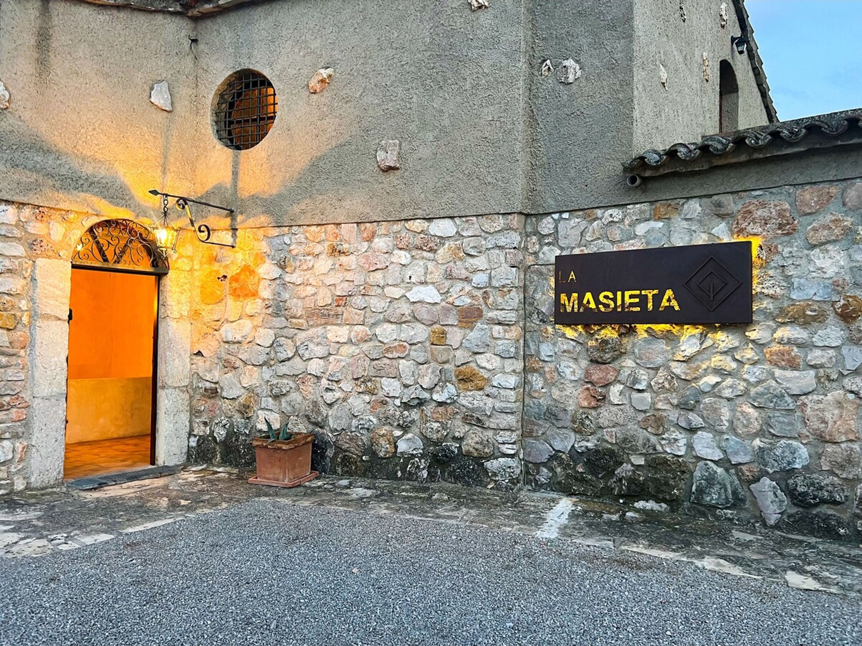 Um edifício de pedra com uma placa que diz "MASIETA" e uma porta de madeira.