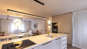 A modern kitchen with a central island, a built-in oven, and a pendant light. - Unik Vacation Train Station (Tarragona)