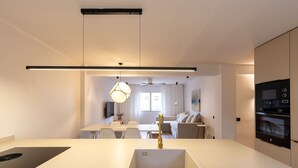 A modern kitchen with a central island, built-in oven, and pendant lighting. - Unik Vacation Train Station (Tarragona)