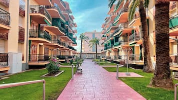 A multi-story hotel with balconies, a central walkway, and palm trees.