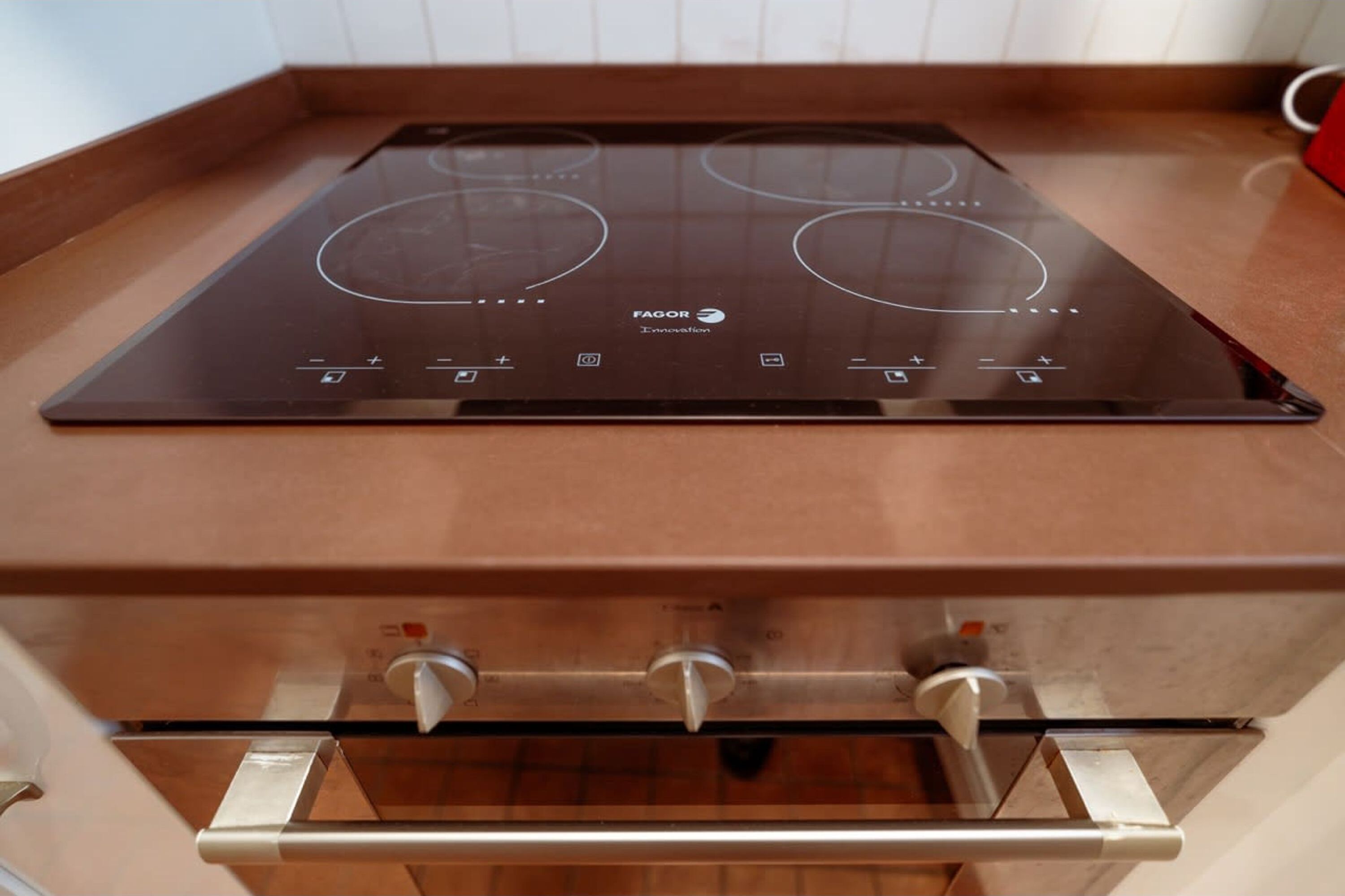 A kitchen with a brown countertop, a Fagor induction cooktop, and a stainless steel oven.
