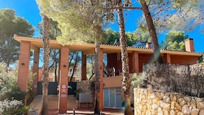A building with a stone wall, a staircase, and a sign indicating a parking area. - Unik Vacation Tamarit (Tarragona)
