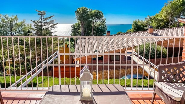 A balcony with a view of the sea, a lantern, and outdoor furniture. - Unik Vacation Tamarit (Tarragona)