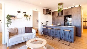 A modern kitchen with a central island, bar stools, and a hanging plant. - Unik Vacation Penthouse (Tarragona)