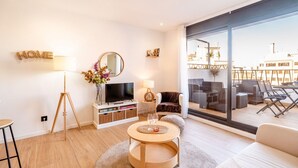 A modern living room with a large window, a flat-screen TV, a round coffee table, and a sofa. - Unik Vacation Penthouse (Tarragona)