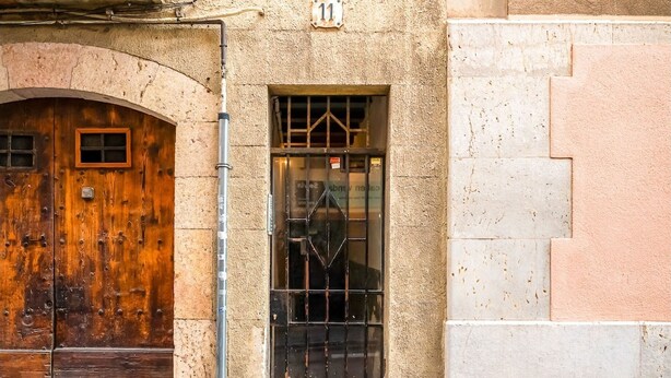 A building facade with a large wooden door, a metal gate, and a stone staircase. - Unik Vacation Congress (Tarragona)