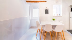 A modern dining area with a white table and chairs, a hanging sign, and a window with blinds. - Unik Vacation Congress (Tarragona)