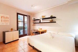 Relax in a serene space with a large bed, desk, and shelf, offering a view of the outside through a large window.