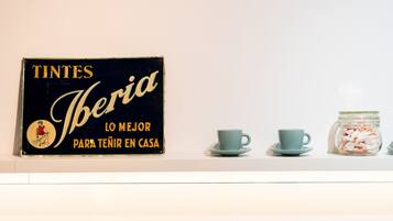 A black sign with gold lettering and a small illustration, two matching blue cups on a saucer, and a jar of cookies.