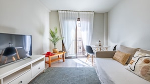 Ein modernes Wohnzimmer mit Flachbildfernseher, einer Couch, einem Couchtisch und einem Essbereich mit Tisch und Stühlen.