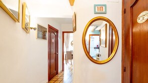 A hallway with a tiled floor, a wooden door, and a mirror on the wall. - Unik Vacation Major in Tarragona (Tarragona)