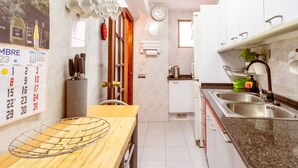 A kitchen with a wooden table, a calendar, a clock, and a sink. - Unik Vacation Major in Tarragona (Tarragona)