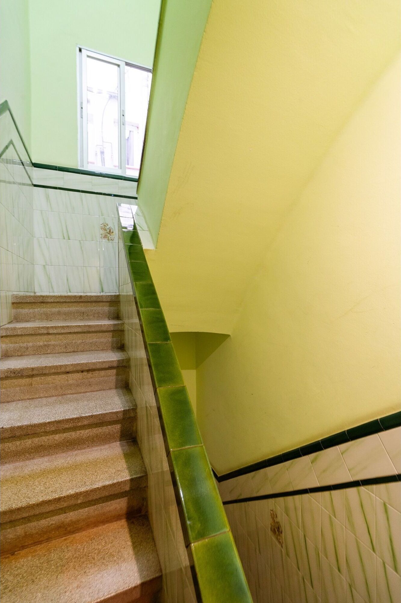 Un escalier avec des marches en marbre et une rampe en verre vert.