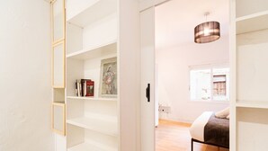 Quarto com cama, piso de madeira e uma grande janela.
