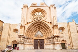 A cathedral with a large rose window, pointed arches, and statues at the entrance. - Unik Vacation Dames i Vells (Tarragona)