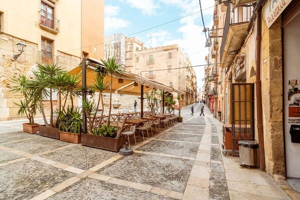 A narrow street with outdoor seating and potted plants.