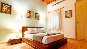 A bedroom with a wooden bed, a nightstand, a lamp, and framed pictures on the wall. - Unik Vacation Dames i Vells (Tarragona)